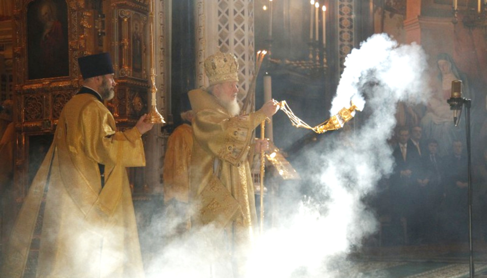 Catholic priest burning incense inside a Church